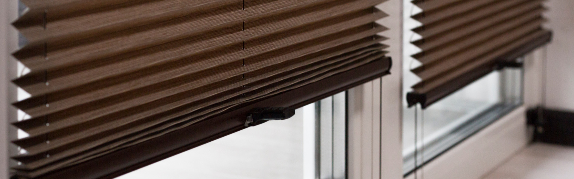 Pleated blinds Cosiflor close up on the window in the interior. Home blinds - cordless pleated modern shades on apartment windows. Brown color fabric.